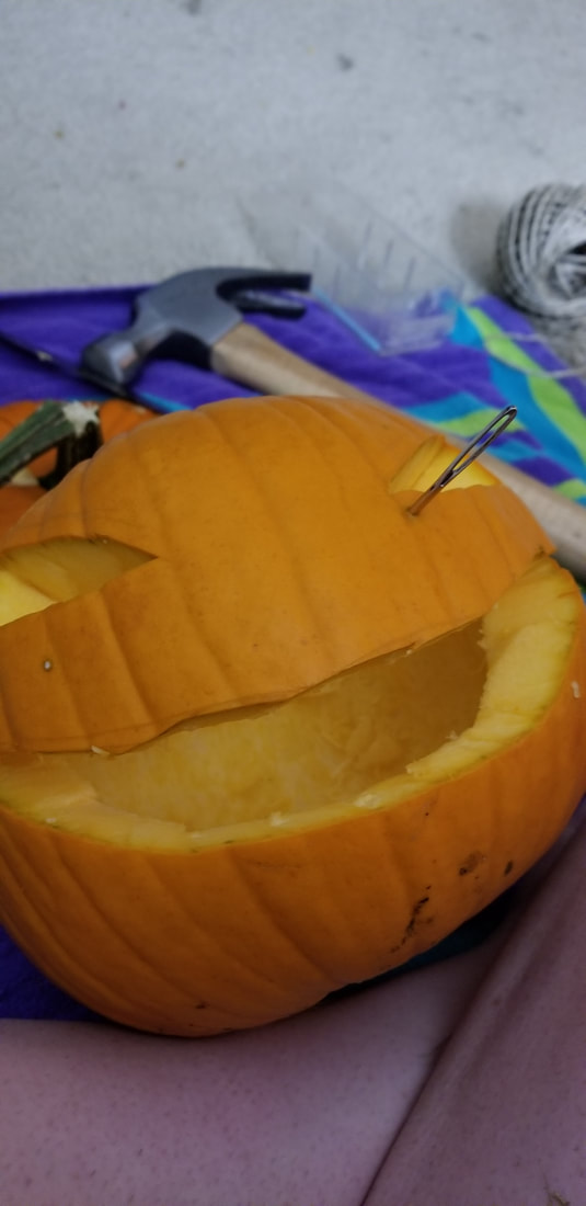 using a needle to sew a pumpkin